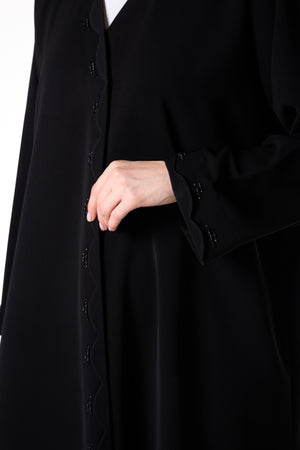 عباية ريا كريب سوداء بتفاصيل خرز على أطراف متموجة